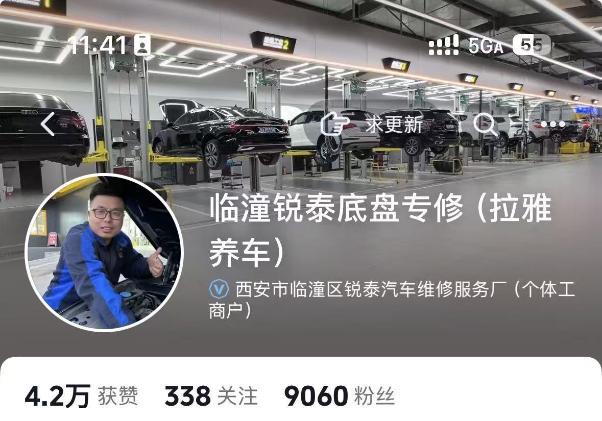 汽修店内景，技师正在举升机旁工作，店内光线充足，设备专业，背景有多个停车位和车辆