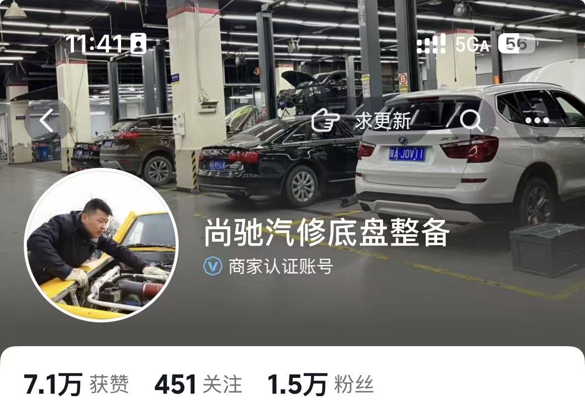 三十岁左右男性技师在明亮汽修店内工作，身穿蓝色工装，正在维修一辆白色轿车，工具整齐摆放，环境整洁有序
